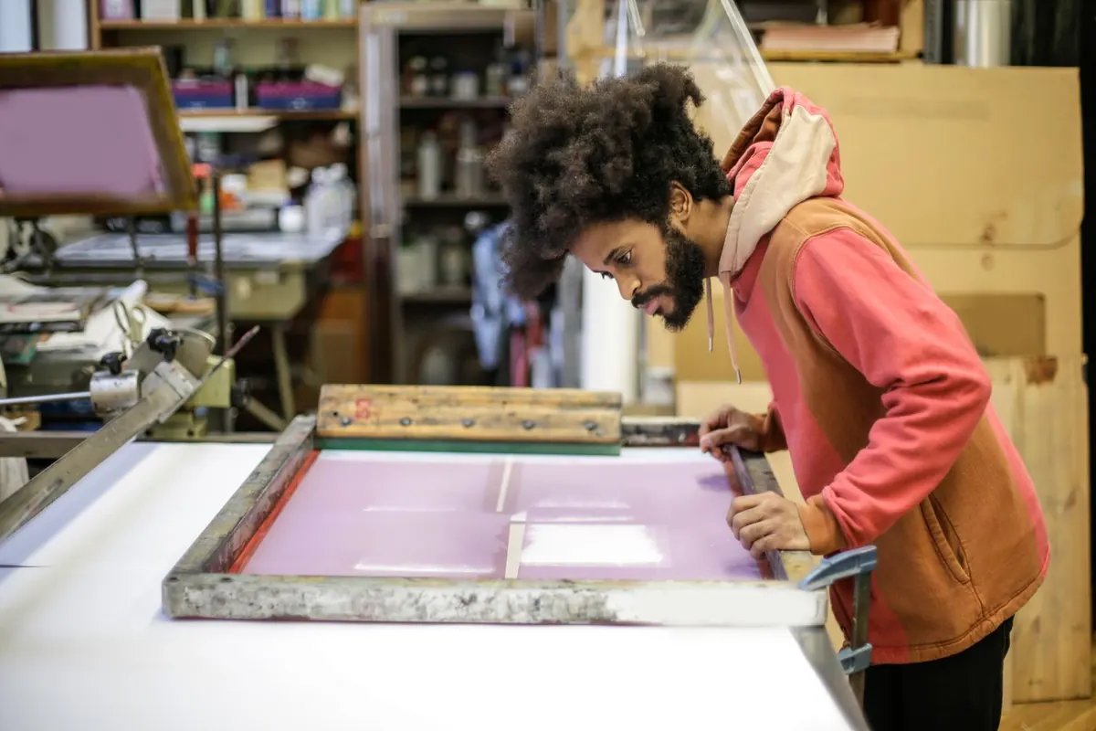 Atölyede serigrafi baskı makinesiyle çalışan baskı ustası